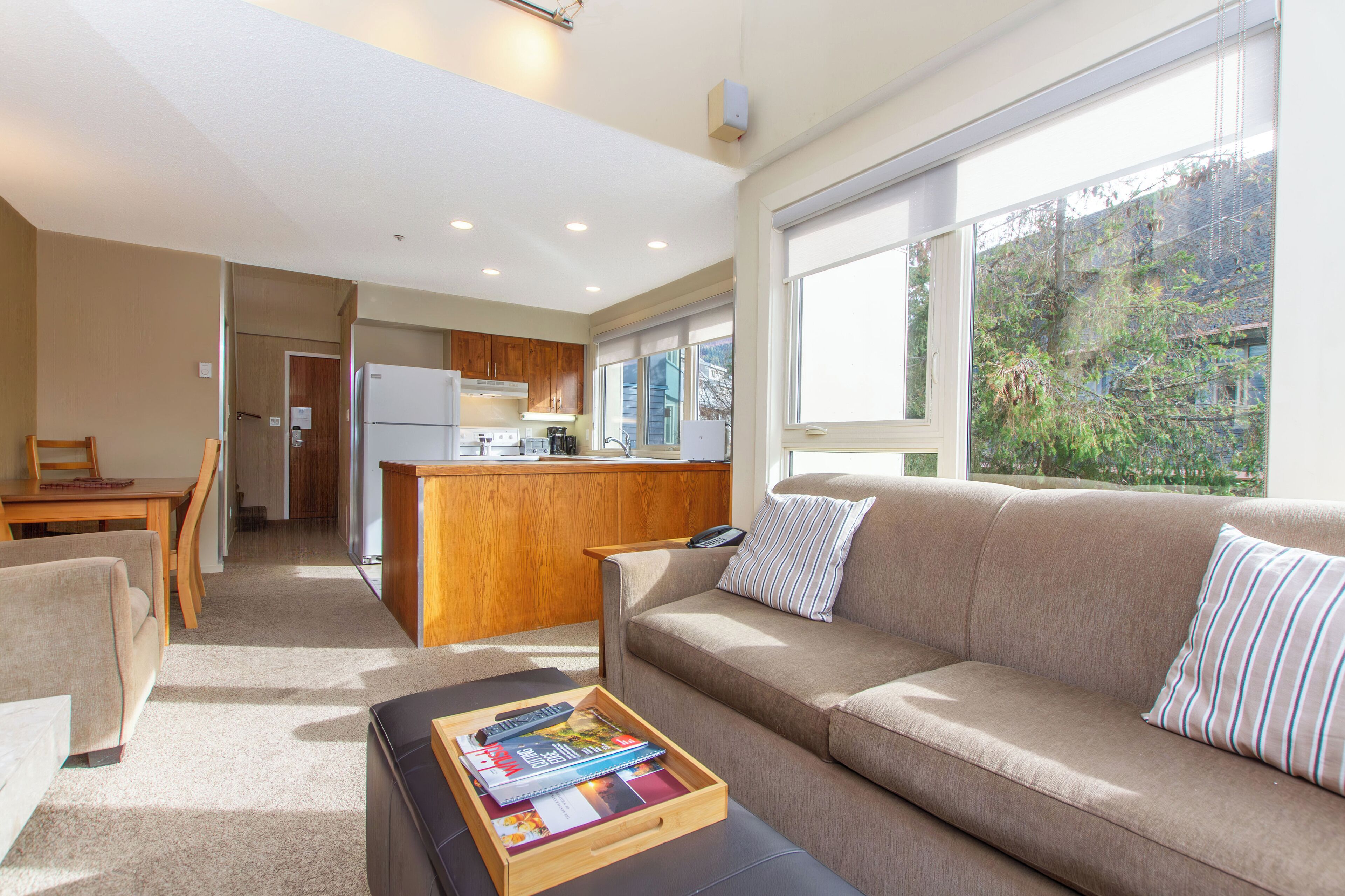 A modern living room with a sofa, coffee table, and a kitchen area in the background.