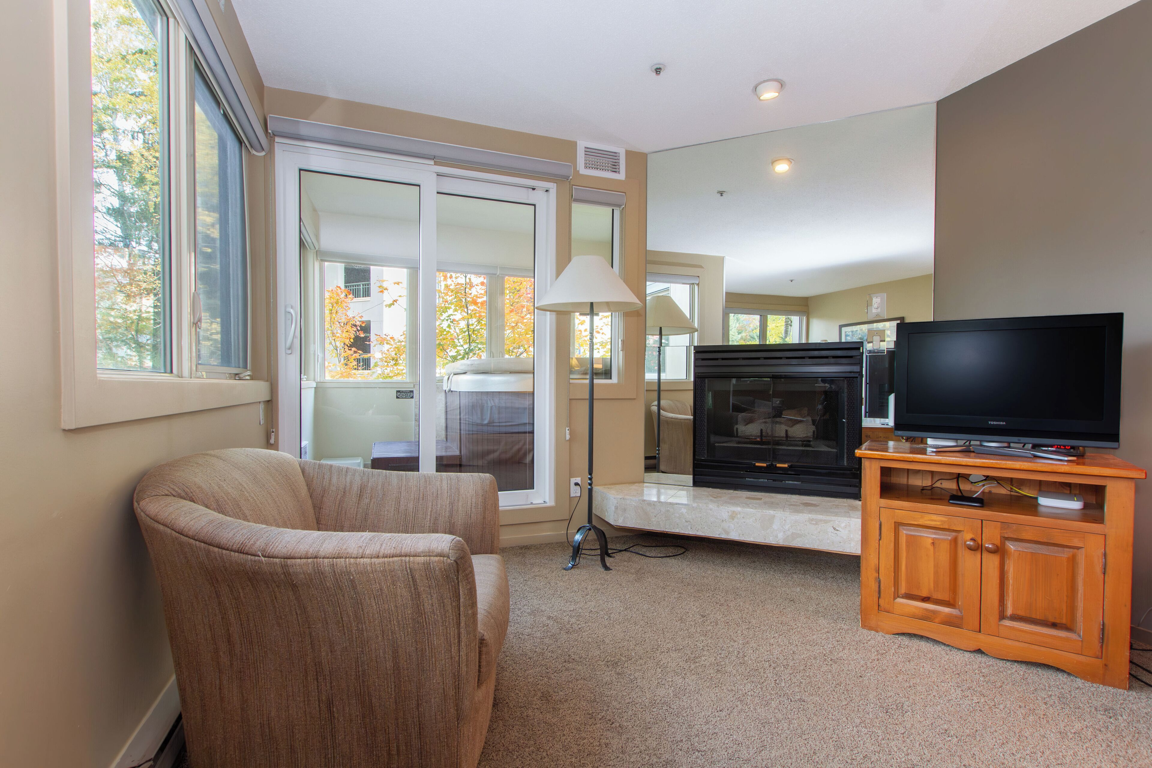 A living room with a sofa, a television on a wooden stand, and a fireplace.