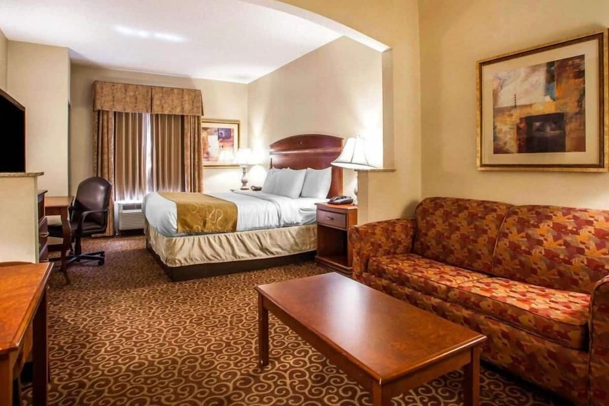 Ein Hotelzimmer mit Bett, einer Sitzecke, einem Schreibtisch, einem Stuhl und einem Fernseher.
