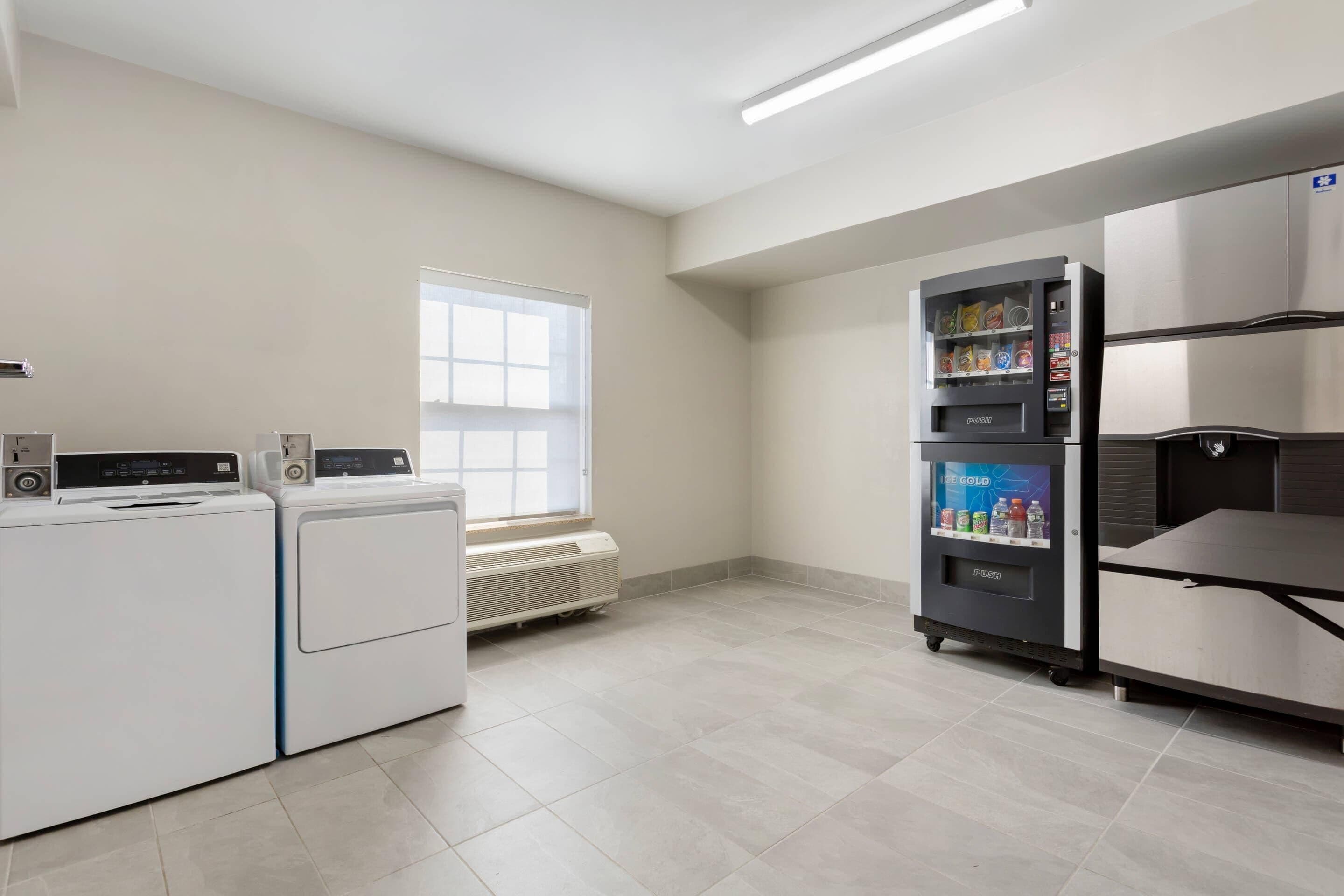 A laundry area with a washing machine and dryer, a vending machine, and a refrigerator.