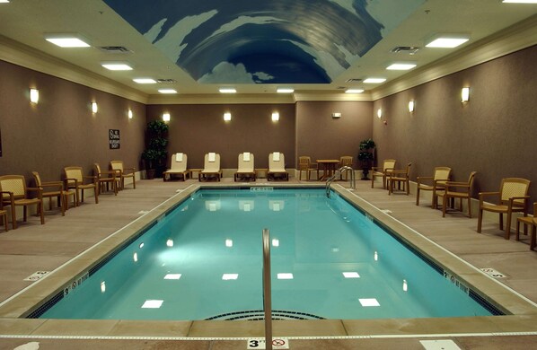 Un vestíbulo de hotel con piscina, sillas y un mural en el techo.