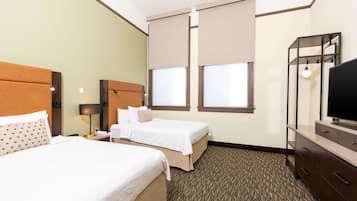 A hotel room with two beds, a TV, a desk, and a lamp.