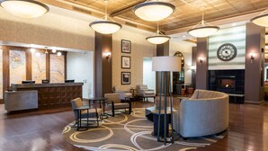 Un hall de hotel con mostrador de recepción, zona de estar y chimenea.