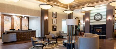 Un hall de hotel con mostrador de recepción, zona de estar y chimenea.
