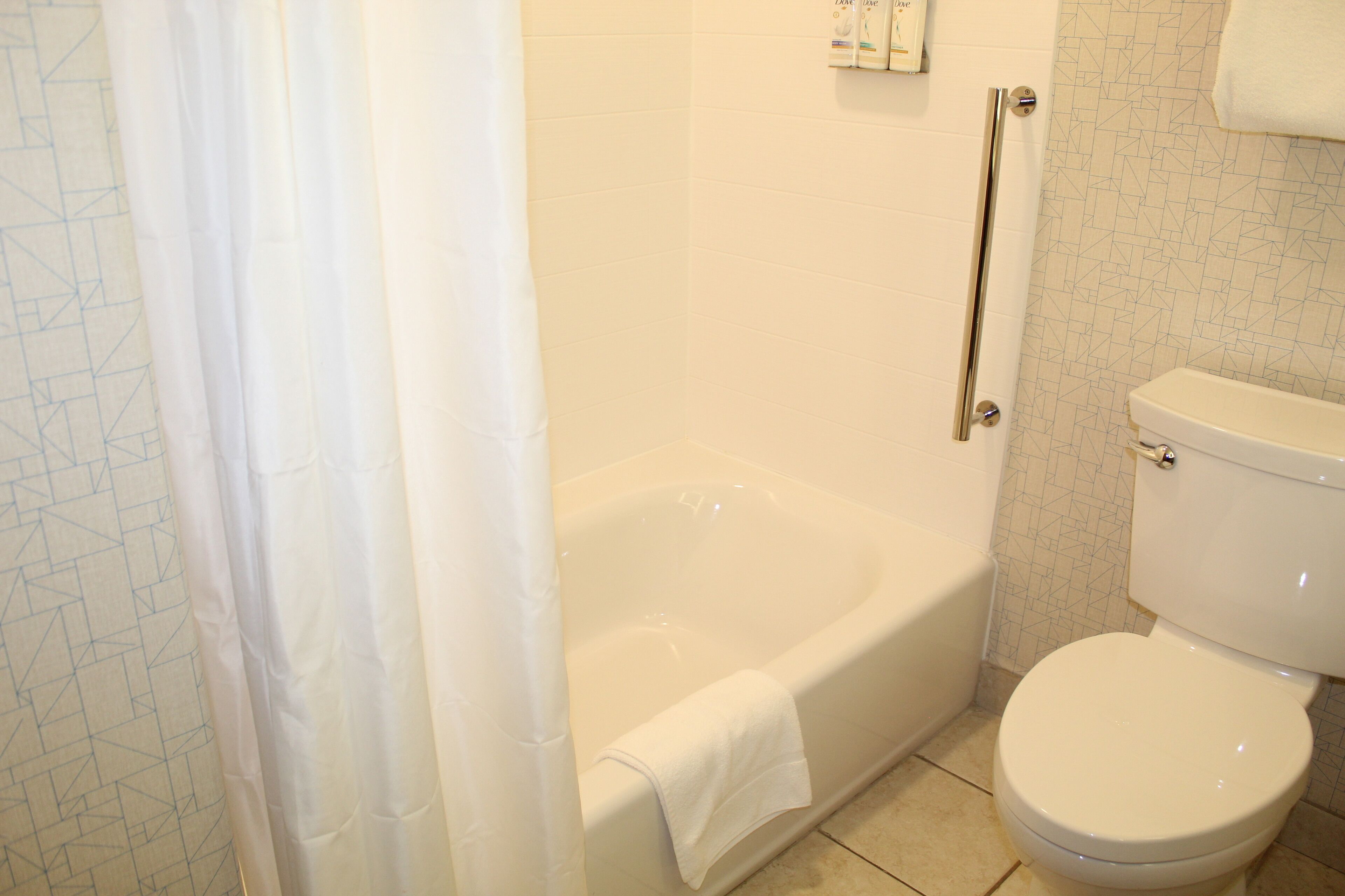 A bathroom with a bathtub, toilet, and a shower curtain.