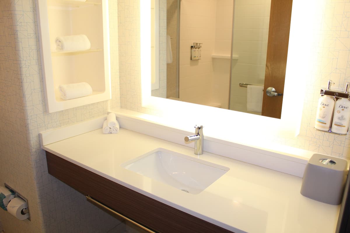 A bathroom with a white sink, a mirror, and a towel rack.