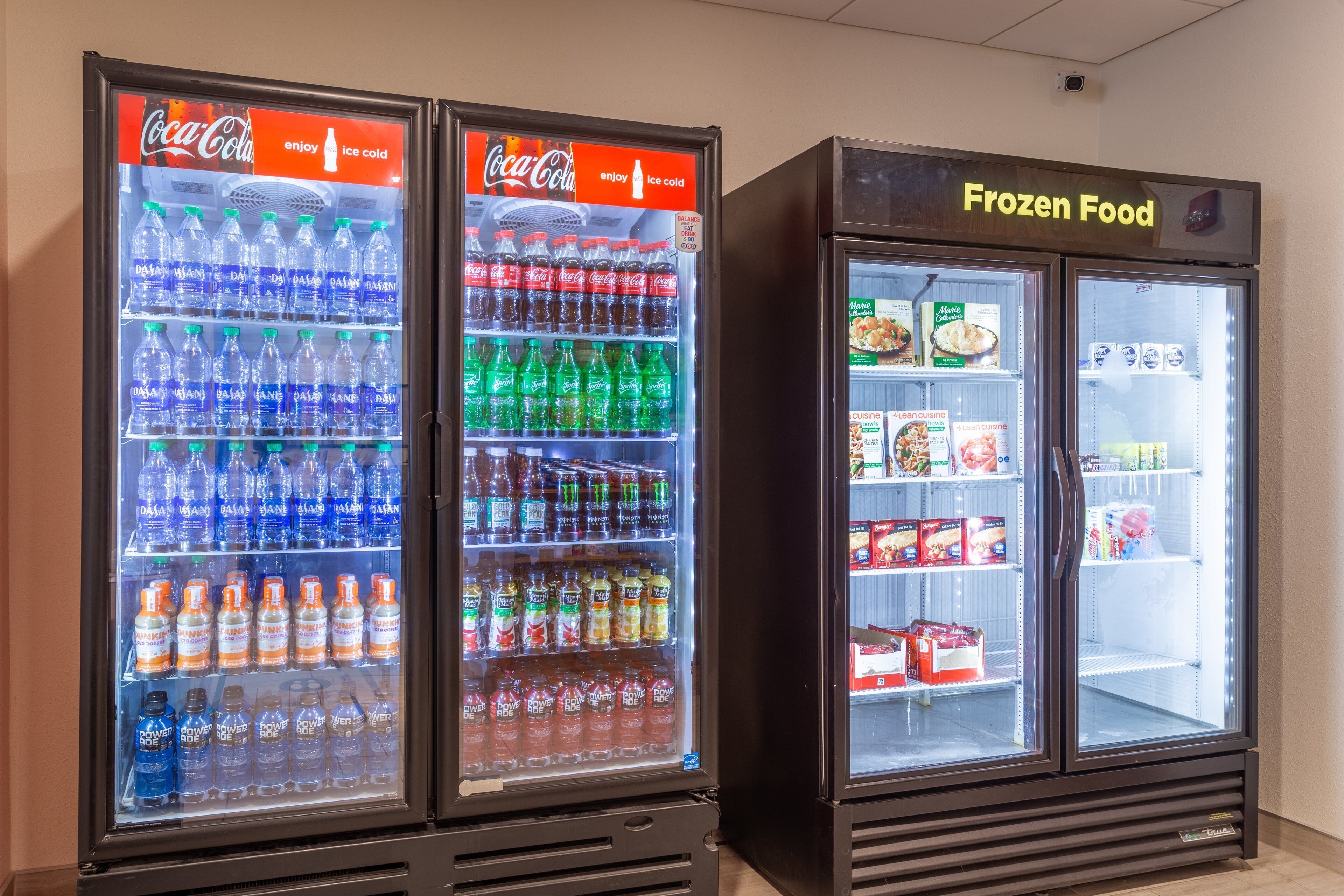 Three beverage vending machines and a frozen food display in a commercial setting.