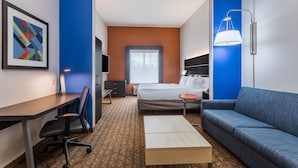 Una habitación de hotel con una cama, un escritorio, una silla, un sofá y una lámpara.