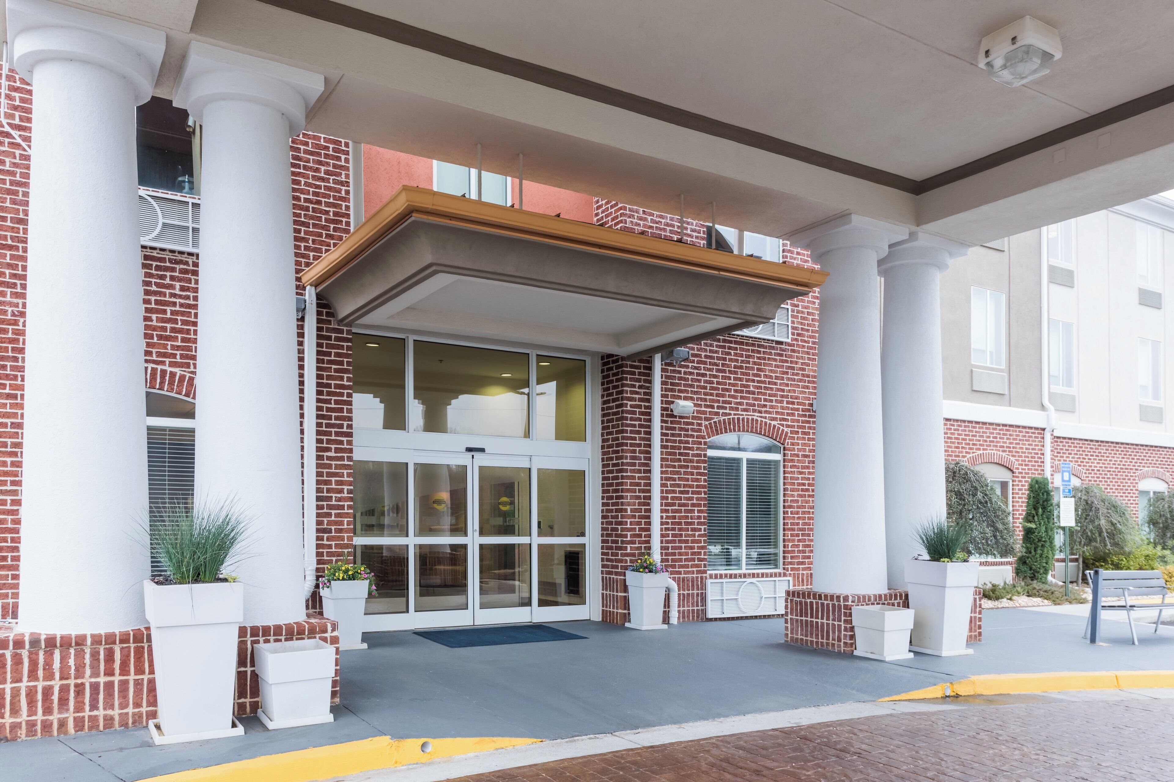 A hotel entrance with a brick facade, large columns, and a covered entrance area.