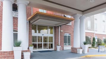A hotel entrance with a brick facade, large columns, and a covered entrance area.
