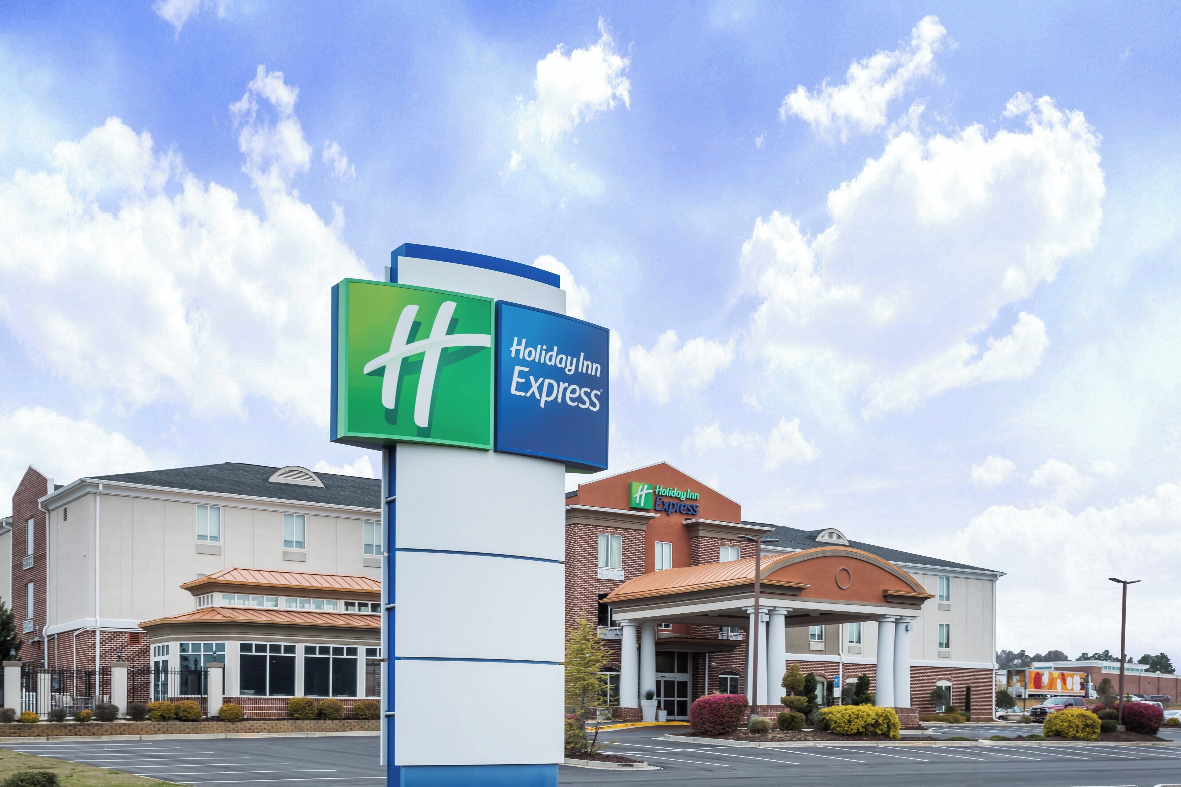 A Holiday Inn Express sign with a clear view of the hotel entrance and parking lot.