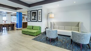 Eine Hotelhalle mit einer Rezeption, einem grünen Sofa, einem weißen Sofa und zwei Sessel.