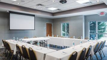 A conference room with a long table, chairs, water bottles, and a projector screen.