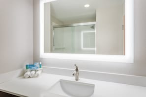 A bathroom with a white sink, a glass shower enclosure, and a mirror above the sink. - Holiday Inn Express Hotel & Suites Bremen by IHG (Bremen)
