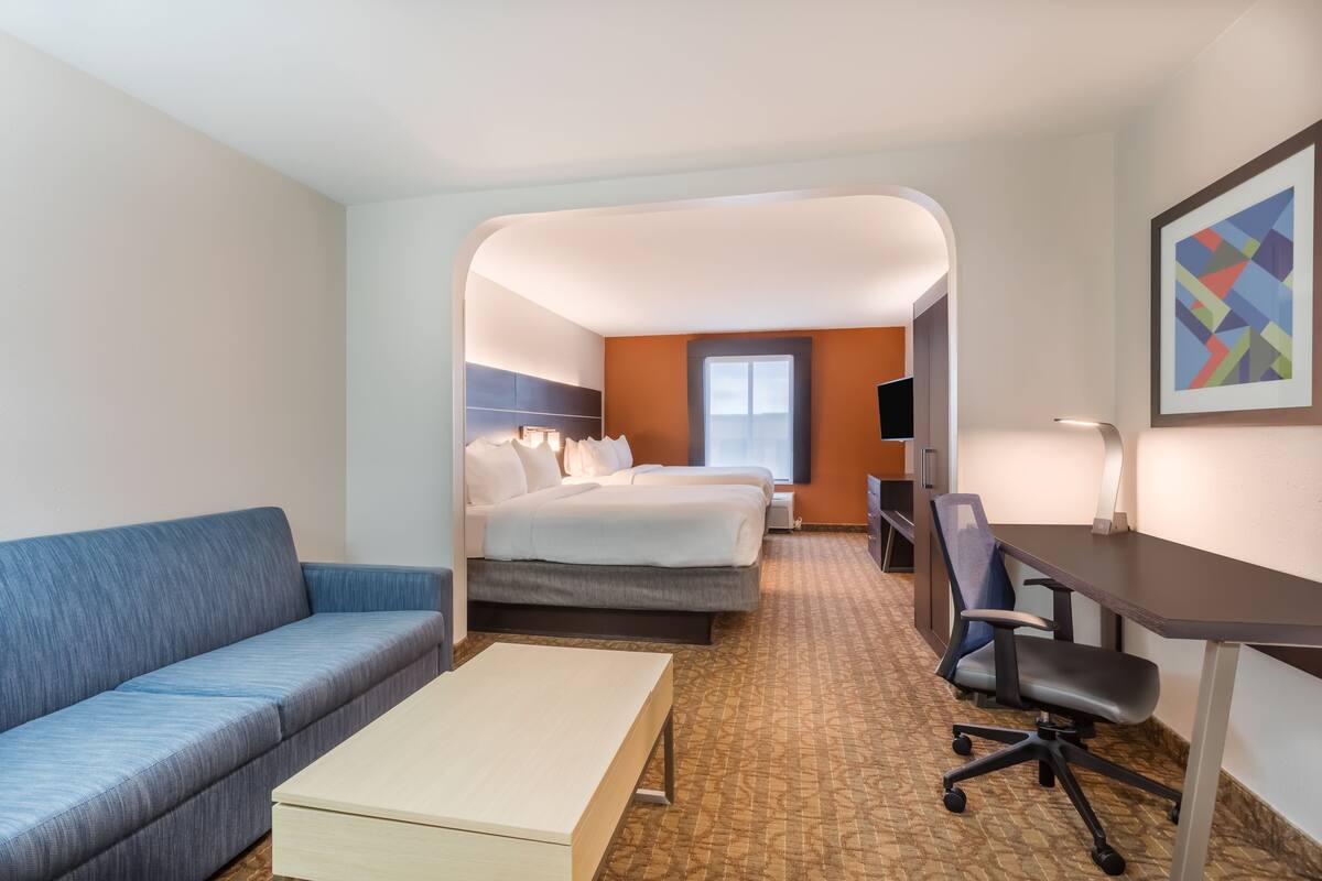 Ein Hotelzimmer mit Bett, Schreibtisch, Sessel, Sofa und kleinem Tisch.