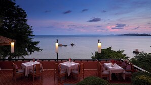 A terrace with tables and chairs overlooking a body of water at dusk. - Renaissance Koh Samui Resort & Spa (Koh Samui)
