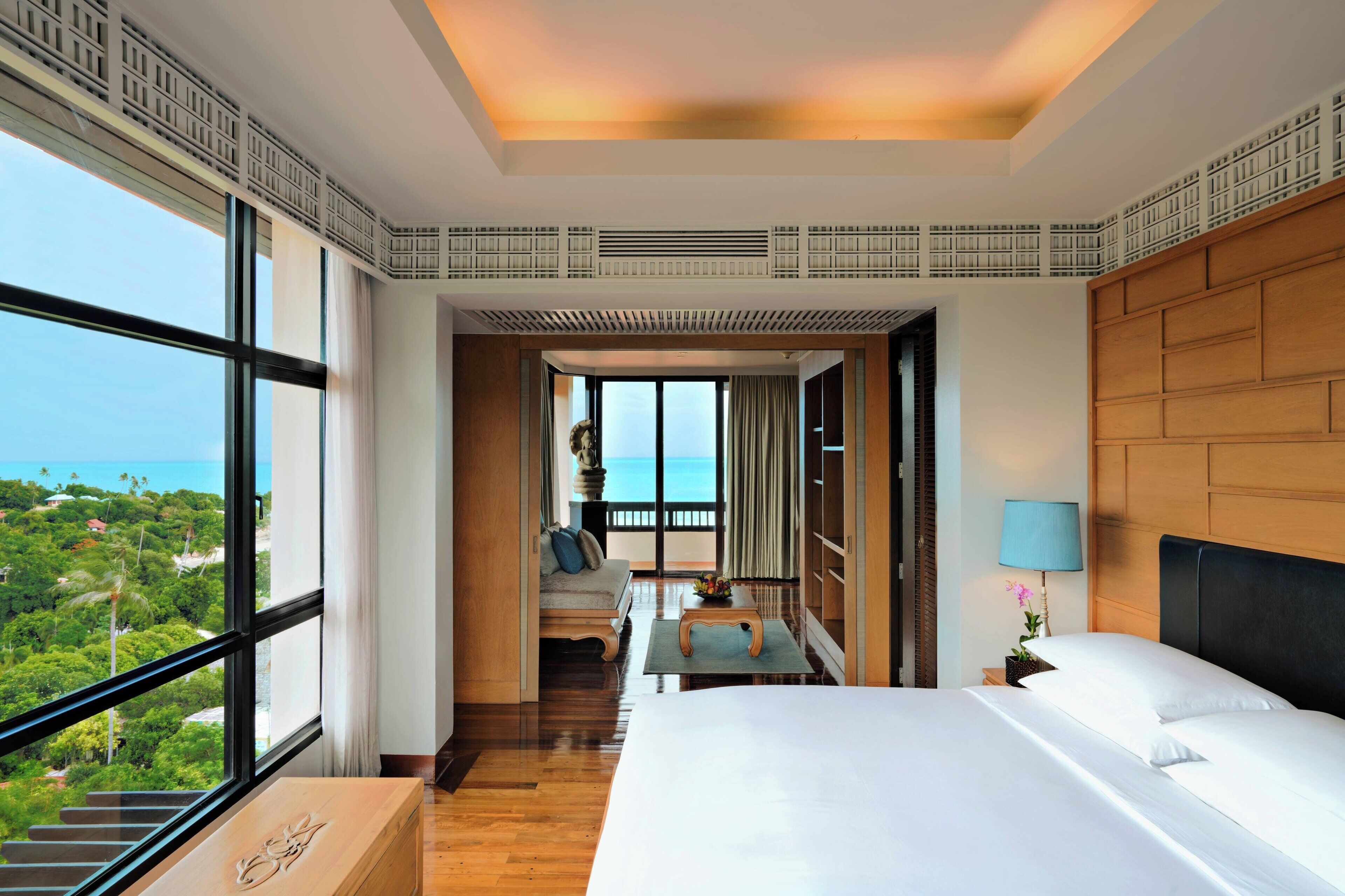 Een hotelkamer met een groot bed, een bureau en uitzicht op de oceaan.