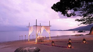 A beach wedding setup with a canopy, tables, chairs, and lanterns. - Renaissance Koh Samui Resort & Spa (Koh Samui)