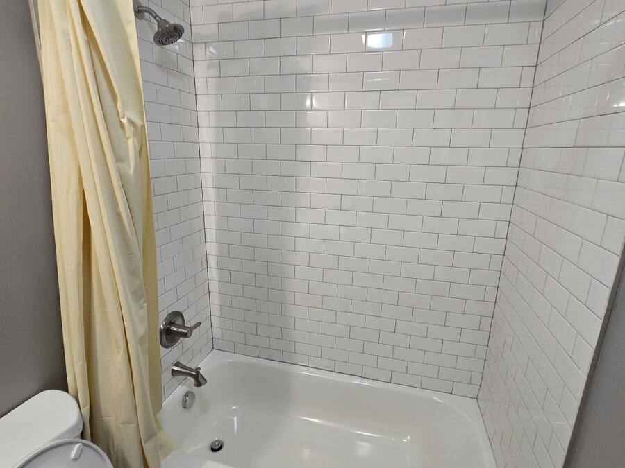 A bathroom with a bathtub, toilet, and shower curtain.