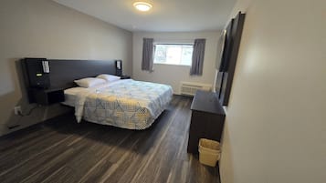 A hotel room with a bed, a desk, a TV, and a window with curtains.