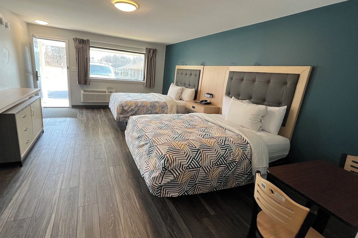 A hotel room with two beds, a desk, and a chair.