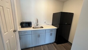 A compact kitchen with a microwave, sink, and black refrigerator.