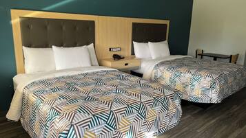 Una camera d'albergo con due letti, ognuno con una coperta a motivi decorativi, una testiera in legno e un comodino con il telefono.