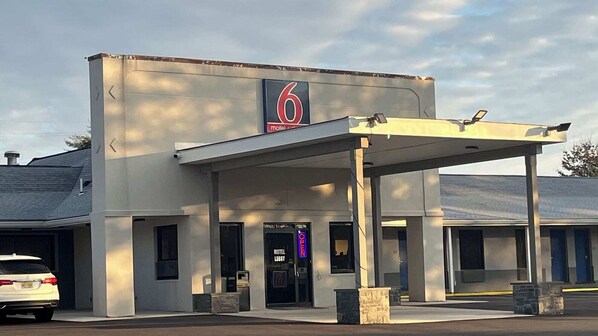 A motel with a large number '6' sign, a covered entrance, and a visible lobby area.