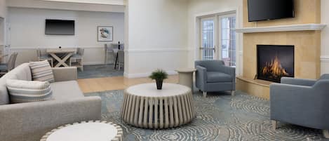 A spacious living room with a fireplace, comfortable seating, and a flat-screen TV mounted above the fireplace.
