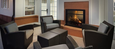 A cozy outdoor seating area with wicker furniture and a fireplace.