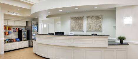 A modern, curved reception desk with a white countertop and a small potted plant.