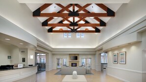 A spacious lobby with a high ceiling, a reception desk, a seating area, and a fireplace. - Residence Inn by Marriott Sandestin at Grand Boulevard (Miramar Beach)