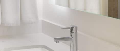 A bathroom with a white sink, chrome faucet, and a mirror above it.