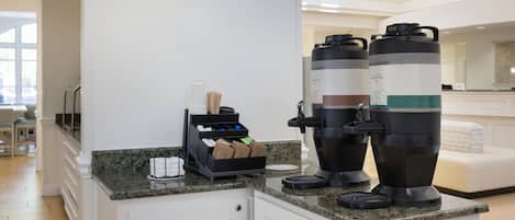 Un área de cocina con una estación de café que incluye dos cafeteras y un escurreplatos con utensilios.