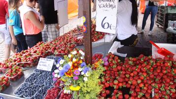 A market stall with strawberries and flowers for sale.