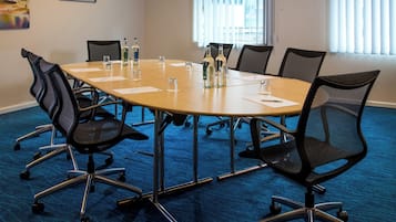 Een vergaderruimte met een ronde tafel, stoelen en waterflesjes.