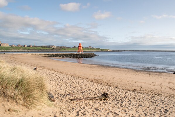 A beach with a lighthouse, sandy shore, and distant buildings. - Holiday Inn Express Newcastle City Centre by IHG (Newcastle-upon-Tyne)