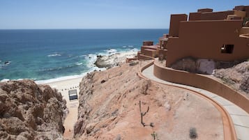 A coastal building with a curved pathway leading to a beach.