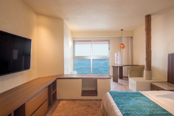 A hotel room with a bed, a desk, a television, a window with a view of the sea, and a chair. - Club Regina Los Cabos managed by Accor (San José del Cabo)