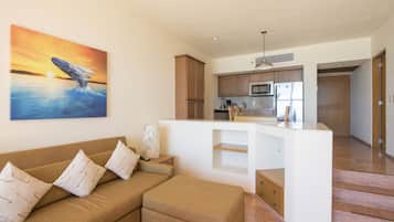 Ein modernes Wohnzimmer mit einer Couch und Hocker, eine Küche mit Holzschränken und ein großes Wandbild von einem Wal.