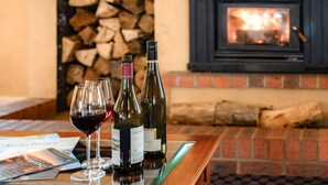 A table with two wine glasses and bottles, a fireplace, and a brick wall.