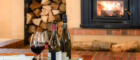 Une table avec deux verres à vin et des bouteilles, une cheminée et un mur en briques.