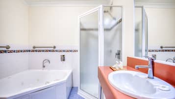 Un baño con bañera, lavamanos y cabina de ducha de vidrio.