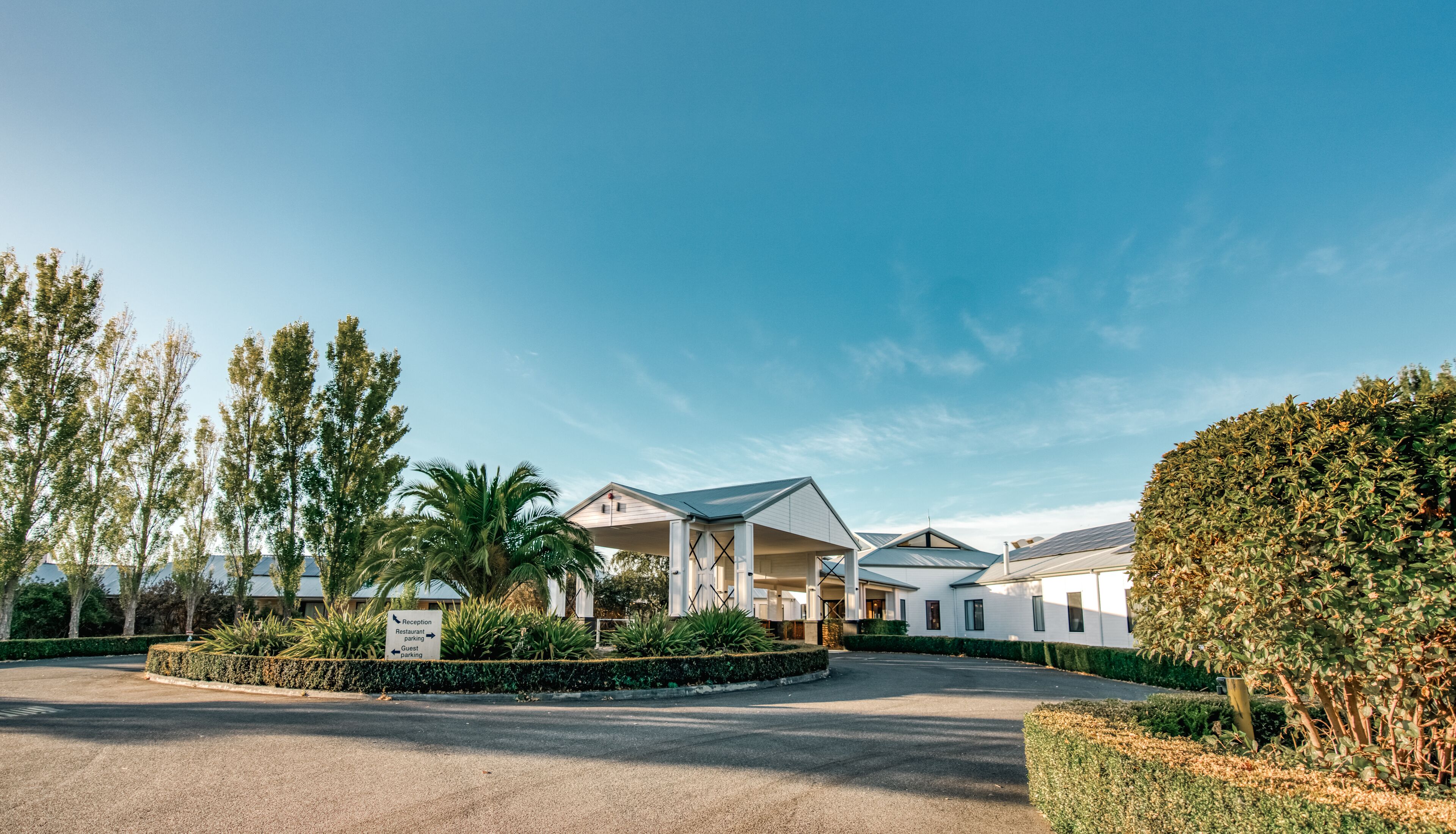 A modern hotel with a reception area, guest parking, and a landscaped garden.