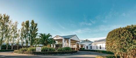A modern hotel with a reception area, guest parking, and a landscaped garden.