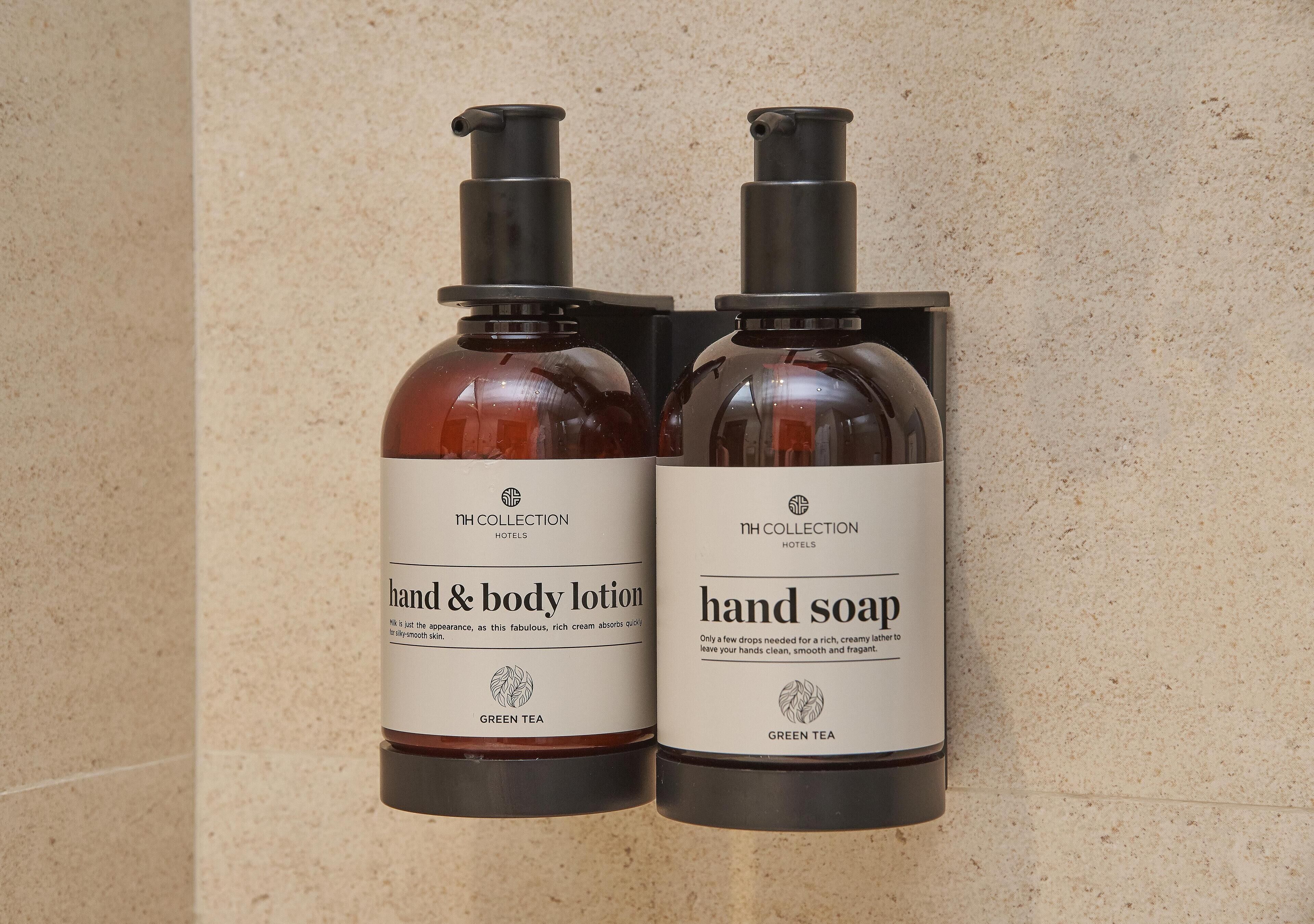 Two bottles of hand and body lotion and hand soap, both labeled with the brand 'Green Tea' and the hotel chain 'NH Collection Hotels'.