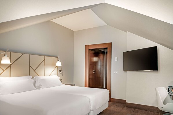 Una habitación de hotel moderna con una cama grande, un televisor de pantalla plana montado en la pared y una puerta de madera.