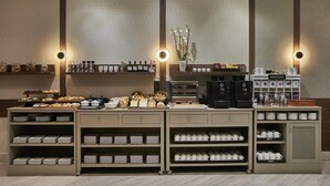 A buffet setup with various food items, coffee machines, and a selection of mugs and plates. - NH Collection León Plaza Mayor (León)