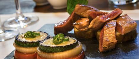 A dish of stuffed zucchini slices with a garnish, served on a slate board.