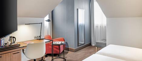 A modern hotel room with a desk, chair, and bed.
